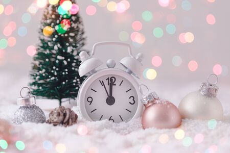 Pink and White glass Christmas balls with an alarm clock on a snowflake background, toned, postcard conceptの写真素材