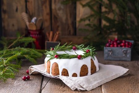 Traditional homemade Christmas fruit cake on the wooden background with fir-tree branches, decorated...