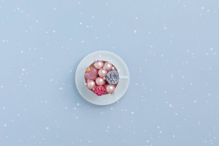 Pink christmas balls and natural cone in the white tea cup on grey background with snowflakes, invitation. holiday menu, postcard conceptの写真素材