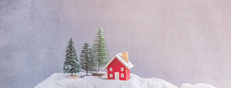 Miniature red wooden house over blurred Christmas decoration background, property real estate investment greetings conceptの写真素材