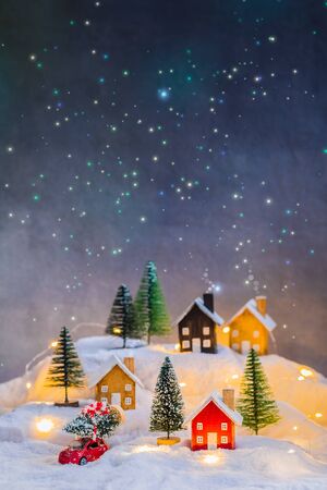 Miniature wooden houses village over blurred Christmas decoration background, property real estate investment greetings conceptの写真素材
