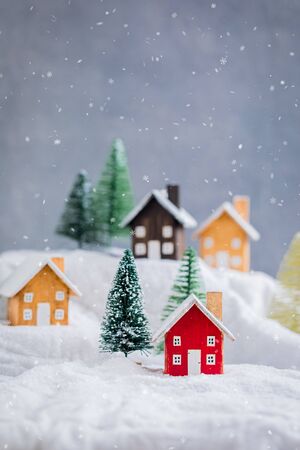 Miniature wooden houses village over blurred Christmas decoration background, property real estate investment greetings conceptの写真素材