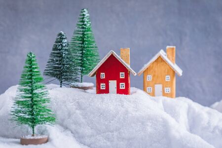 Miniature wooden houses village over blurred Christmas decoration background, property real estate investment greetings conceptの写真素材