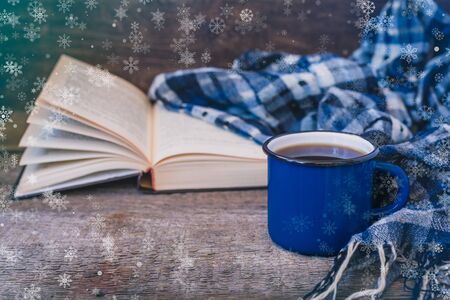 Classical blue colored cup of coffee with a knitted scarf on a wooden background, winter postcard conceptの写真素材