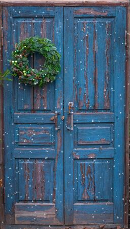Christmas handmade wreath with green balls, cinnamon sticks, cones, stars on blue wooden rustic door, postcard conceptの写真素材