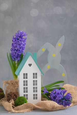 Easter spring daylight postcard composition with fresh blue hyacinth potted and miniature wooden house, happy family living conceptの写真素材