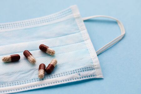 Tablets on blue background with surgical protective mask, medicine drugs concept, copy space