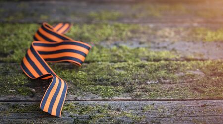 St. George ribbon on natural moss wooden background, symbol of Victory Day May 9, tonedの写真素材