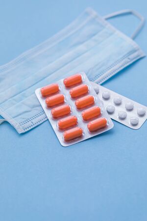 Tablets and pills on blue background with surgical protective mask, medicine drugs concept, copy spaceの写真素材
