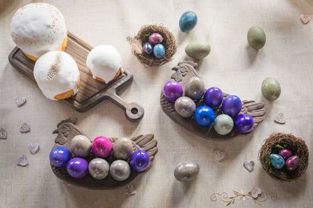 Naturally dyed Easter quail and hen's eggs, nest, Easter cakes, wooden hearts on linen background, flat lay, retro styled spring holiday greeting postcard conceptの写真素材