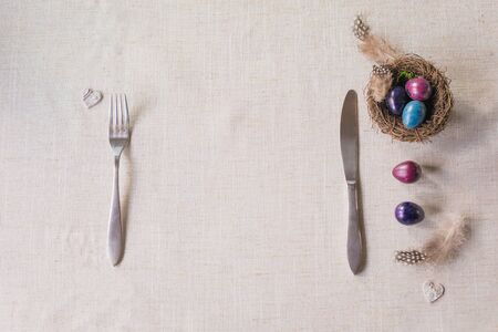 Easter festive spring table setting decoration, naturally dyed quail eggs in nests, feathers, wooden hearts, family dinner or breakfast conceptの写真素材