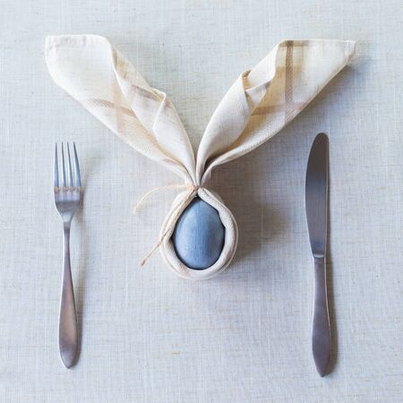 Easter festive spring table setting decoration, bunny ears shaped napkins, dyed eggs, family dinner...