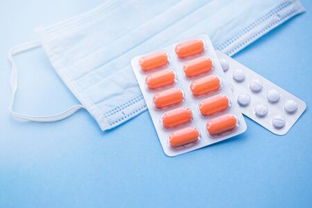 Tablets and pills on blue background with surgical protective mask, medicine drugs concept, copy spaceの写真素材