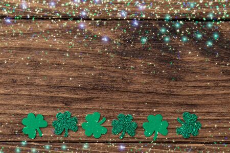 St Patrick day background with shamrock clover leaf on wood, Irish festival symbol, toned, with fairy dust texture, copyspaceの写真素材