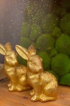 Golden rabbits on wooden background, Easter greeting card concept, toned, with dust textureの写真素材