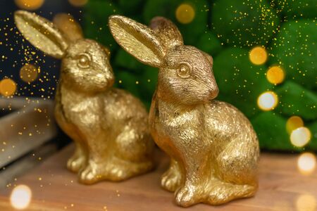 Golden rabbits on wooden background, Easter greeting card concept, toned, with dust textureの写真素材