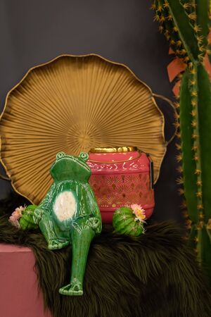 Art Deco still life composition with a ceramic frog, geometric textured pink vase, golden dish, cactus, retro design conceptの写真素材