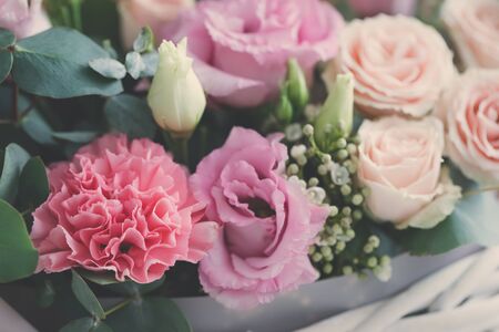 Pastel trend colored flowers in white basket isolated, floristic wedding present background, March...