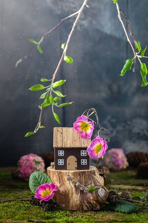 Miniature wooden toy house cottage with pink flowers on moss background, spring Easter, Earth Day postcard conceptの写真素材