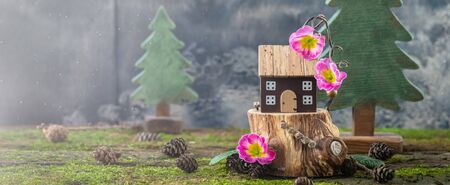 Miniature cozy fairy wooden house cottage with pink flowers on moss background, spring Easter, Earth Day postcard conceptの写真素材