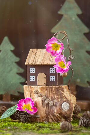 Miniature cozy fairy wooden house cottage with pink flowers on moss background, spring Easter, Earth Day postcard conceptの写真素材