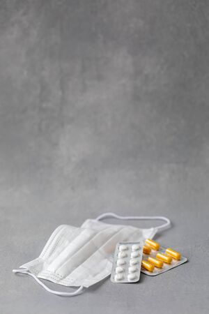 Tablets and pills on grey background with surgical protective mask, medicine drugs concept, copy spaceの写真素材