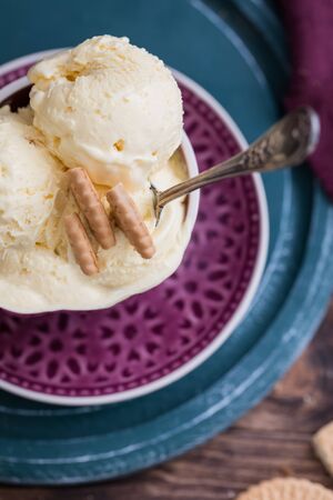 Vanilla yogurt flavour homemade ice cream balls in a cup, with biscuits, summer sundae on rustic backgroundの写真素材