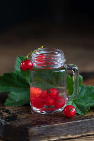 Homemade liqueur in shot glass with red current berries on the table. Fruit flavor alcohol drink...