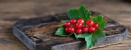 Fresh red currant with green leaves on rustic wooden table top view with copy spaceの写真素材