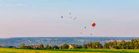 Colorful hot air balloons flying over the countryside in summerの写真素材