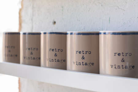 A row of vintage beige tea and coffee mugs on wooden white shelf, selective focusの写真素材