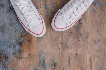 A pair of white canvas shoes or sneakers on a wooden background, toned vintageの写真素材