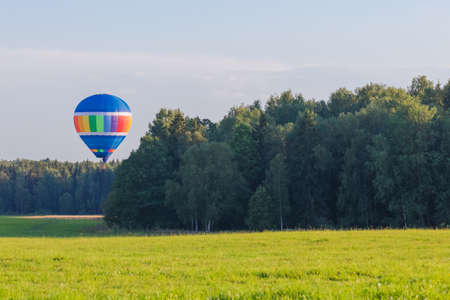 Colorful hot air balloon flying over the countryside in summerの写真素材