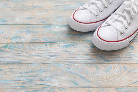 A pair of white canvas shoes or sneakers on a wooden background, toned vintageの写真素材