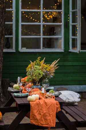 Fall themed holiday table setting arrangement for a seasonal party, glasses, pumpkins, candles, field flowersの写真素材