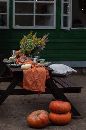 Fall themed holiday table setting arrangement for a seasonal party, glasses, pumpkins, candles, field flowersの写真素材