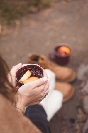 Traditional mulled wine with orange, cinnamon, apples and anise in the mug in woman's hands, selective focus,の写真素材