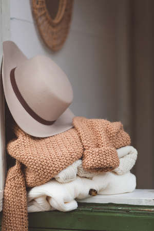 Warm and cozy hygge concept with white and beige sweaters and a hat at a windowsill, tonedの写真素材