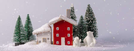 Miniature fairy tale red and white wooden houses and two polar bears toys over blurred Christmas decoration background, property real estate investment greetings conceptの写真素材