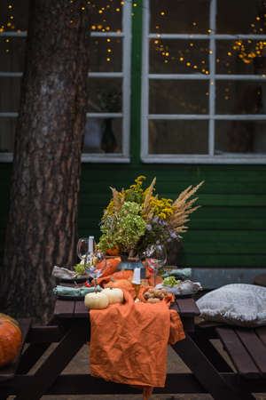 Fall themed holiday table setting arrangement for a seasonal party, glasses, pumpkins, candles, field flowersの写真素材