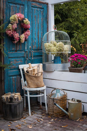Autumn garden decoration set near the house, hydrangea wreath, old instruments, colorful flowers potted, old blue doorsの写真素材