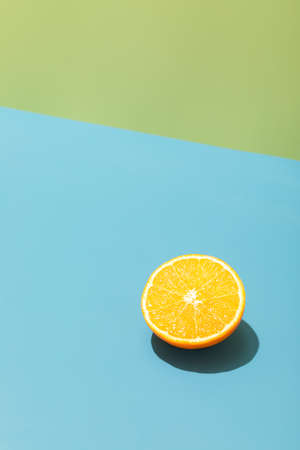 Minimalistic concept with half a fresh lemon isolated on a bright blue and green background, deep dark hard shadowsの写真素材