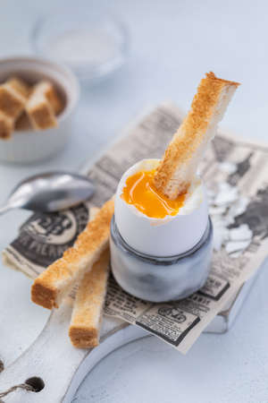 Soft-boiled egg in an eggcup breakfast with toasts and coffee on the wooden backgroundの写真素材