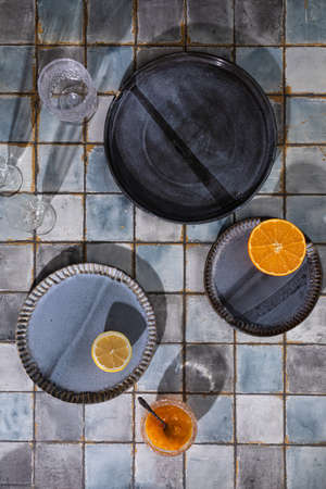 Sunny lunch, siesta table setting on blue and grey ceramic tile background table with long shadowsの写真素材
