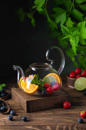 Fruit red tea with berries in glass teapot on wooden backgroundの写真素材