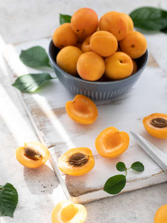 Fresh apricots in a blue bowl on a white wooden backgroundの写真素材