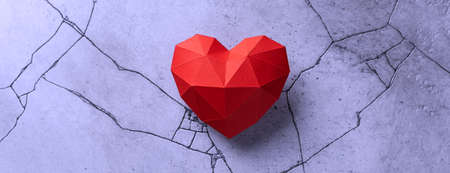 Red paper heart isolated on very peri cracked concrete backgroundの写真素材
