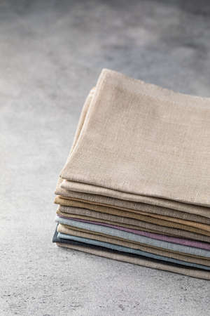 A pile of four folded dull-colored eco-friendly natural linen fabric on a rustic background, bannerの写真素材