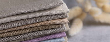 A pile of four folded dull-colored eco-friendly natural linen fabric on grey backgroundの写真素材