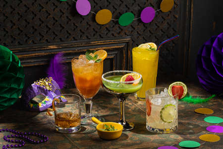 Alcoholic beverage cocktails, purple, green and gold Mardi Gras beads, masks decoration on dark rustic background, festive holiday conceptの写真素材